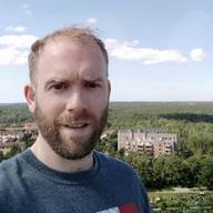 A person with a beard and a forest in the background

Description automatically generated